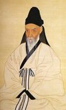 Yi Chae was a scholar who lived in late Joseon. This shows him at the age of 59. He is donning a black hat known as <i>dongpagwan</i> and a <i>simui</i>, a white scholar’s jacket. The white jacket has a collar in a contrasting black band. A large sash woven with threads in five colors, representing the four cardinal directions and the center, drapes down from the mid-chest level.