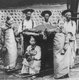 Korea: Three young women with a <i>gama</i> or palanquin and bearers, early 20th century